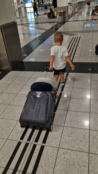 Kisgyerek bőröndöt húz a repülőtéren az egyiptomi utazás előtt